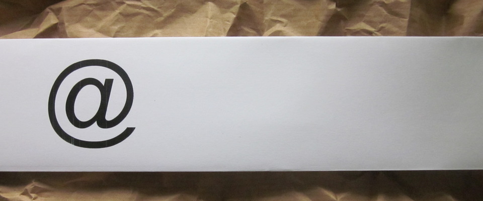 Foto @-Zeichen auf weißem Papier vor gecrashtem Packpapierhintergrund